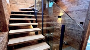 A modern staircase with wooden steps and glass railings. - Hideaway Design Chalet (Reith bei Kitzbühel)