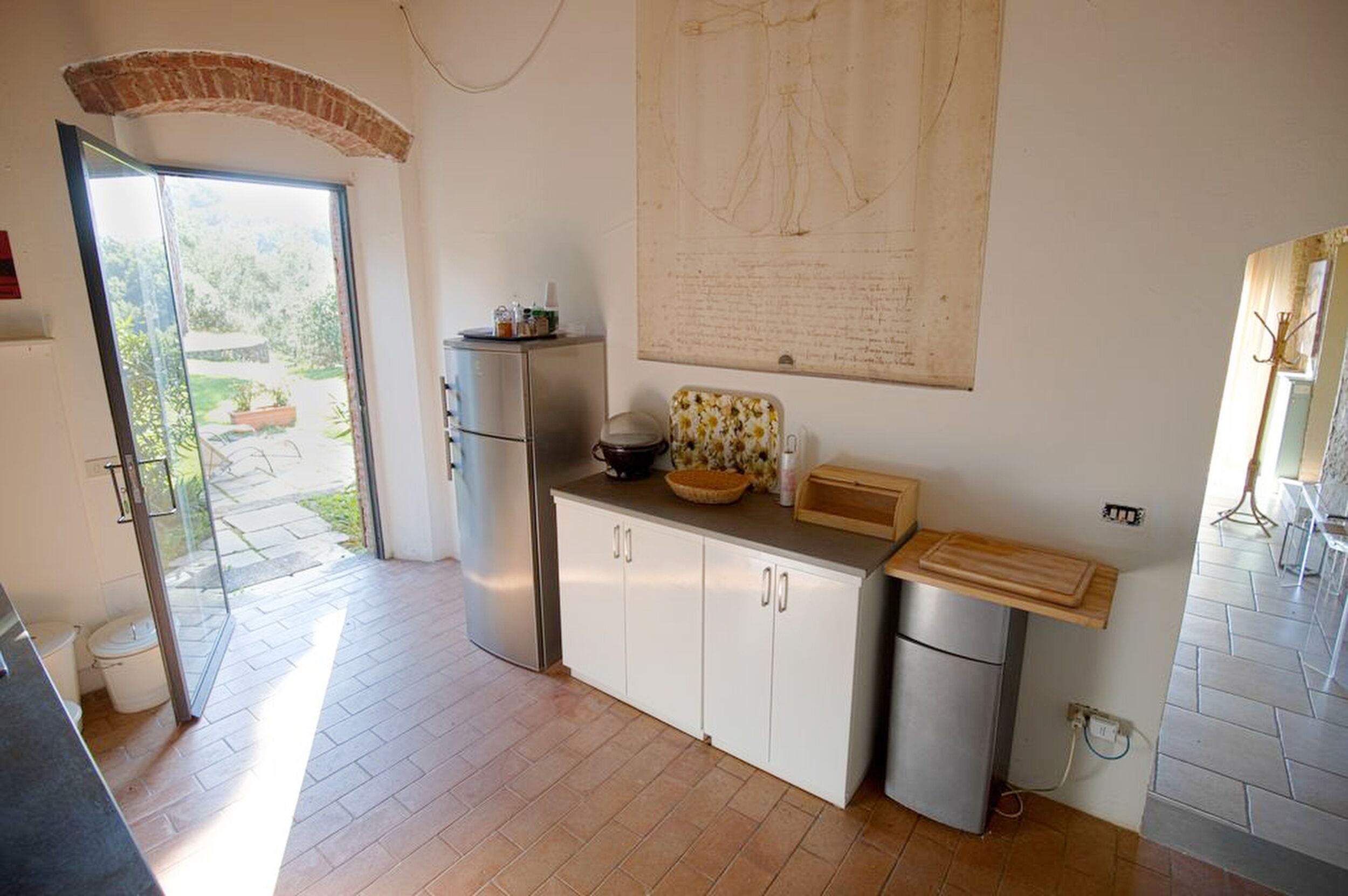 Eine moderne Küche mit weißen Schränken, einem Edelstahlkühlschrank und einem großen Fenster mit Blick ins Freie.
