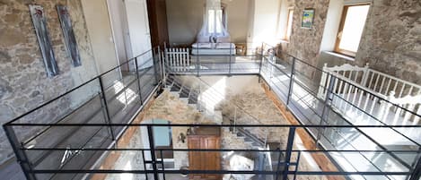 Un intérieur spacieux avec de hauts plafonds, des murs en pierre et un escalier central.