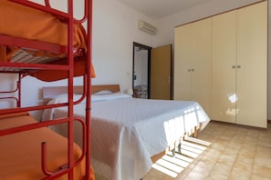 Quarto com beliches, uma cama de solteiro, guarda-roupa e ar condicionado.