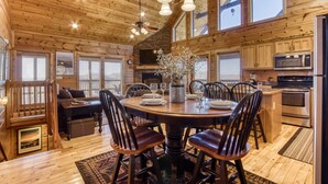A wooden interior with a dining table, chairs, a fireplace, and a kitchen area. - Whiskey's mountain lodge, Mtn Views, Game Room, $560 FREE tickets each paid day (Sevierville)