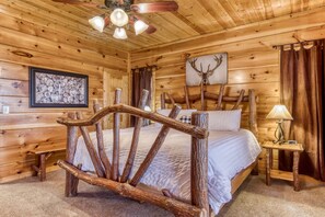 A wooden cabin bedroom with a rustic bed frame, a ceiling fan, a framed picture of shells, and a deer head artwork. - Whiskey's mountain lodge, Mtn Views, Game Room, $560 FREE tickets each paid day (Sevierville)