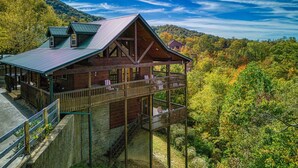 A cabin with a balcony, surrounded by autumn foliage and a mountainous backdrop. - Whiskey's mountain lodge, Mtn Views, Game Room, $560 FREE tickets each paid day (Sevierville)