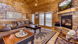 A cozy log cabin interior with a fireplace, wooden walls, a sofa, and a rocking chair. - Whiskey's mountain lodge, Mtn Views, Game Room, $560 FREE tickets each paid day (Sevierville)