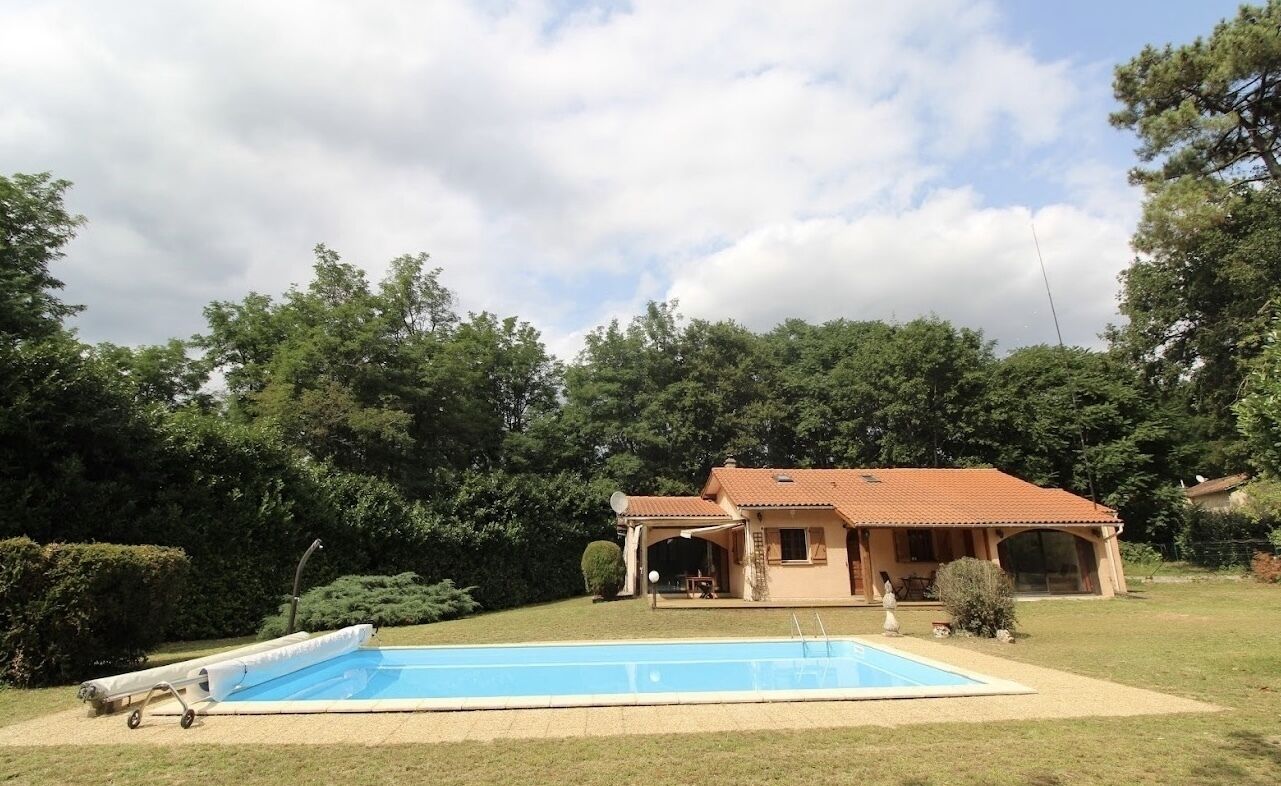 Une maison avec une piscine, entourée d’un jardin et d’arbres.