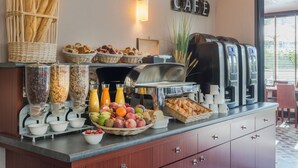 Un bufé de desayuno con diferentes opciones de comida, máquinas de café y un cartel que dice "CAFE".