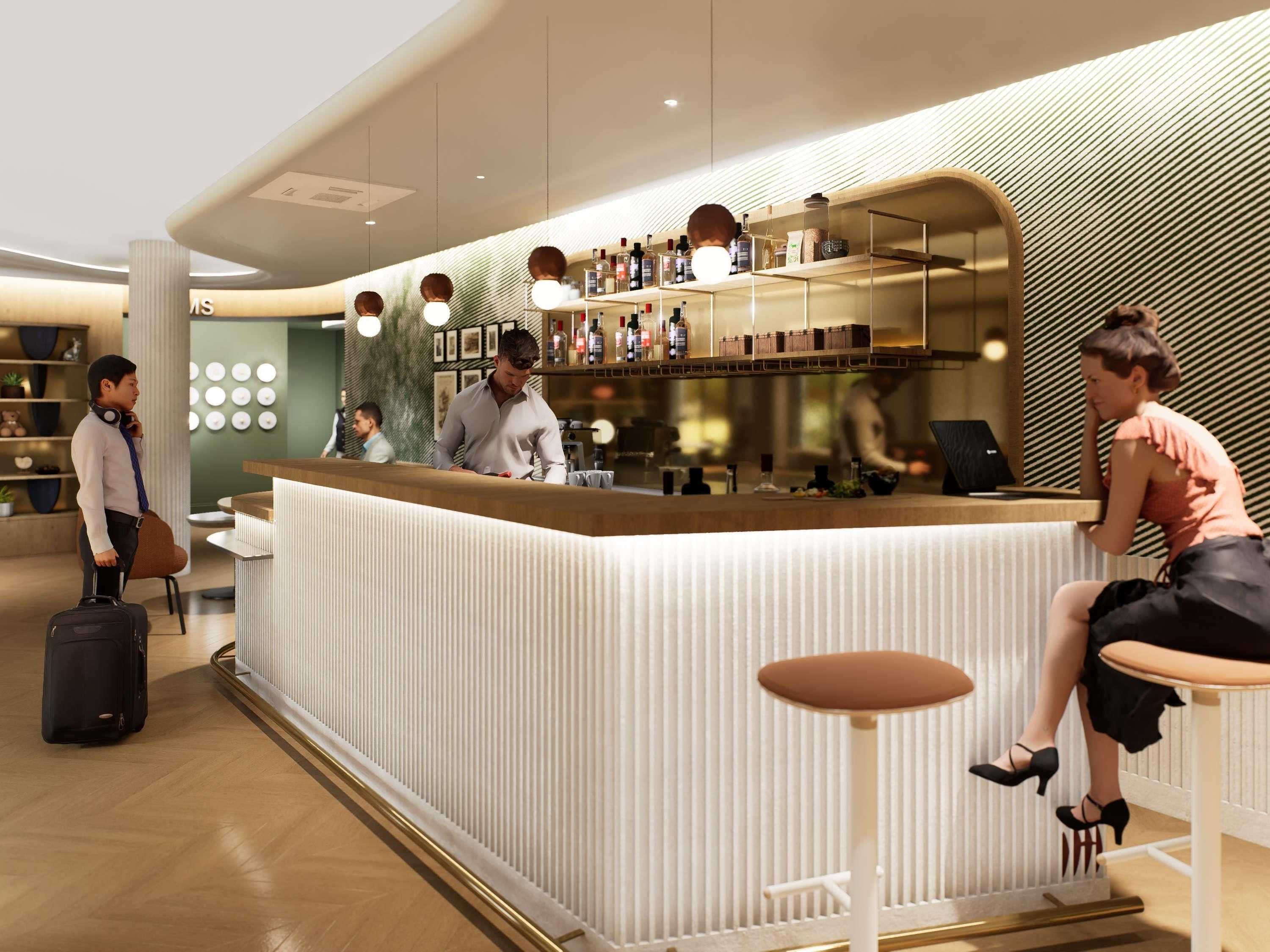 Un área de bar moderna con mostrador, taburetes y una variedad de botellas y vasos.