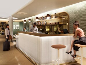 Un espace bar moderne, doté d’un comptoir, de tabourets et d’une variété de bouteilles et de verres.