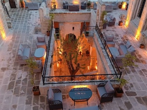 A courtyard with stone flooring, outdoor seating, and potted plants.