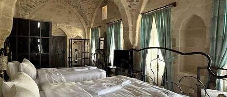 A room with a stone ceiling, large beds, and arched doorways.