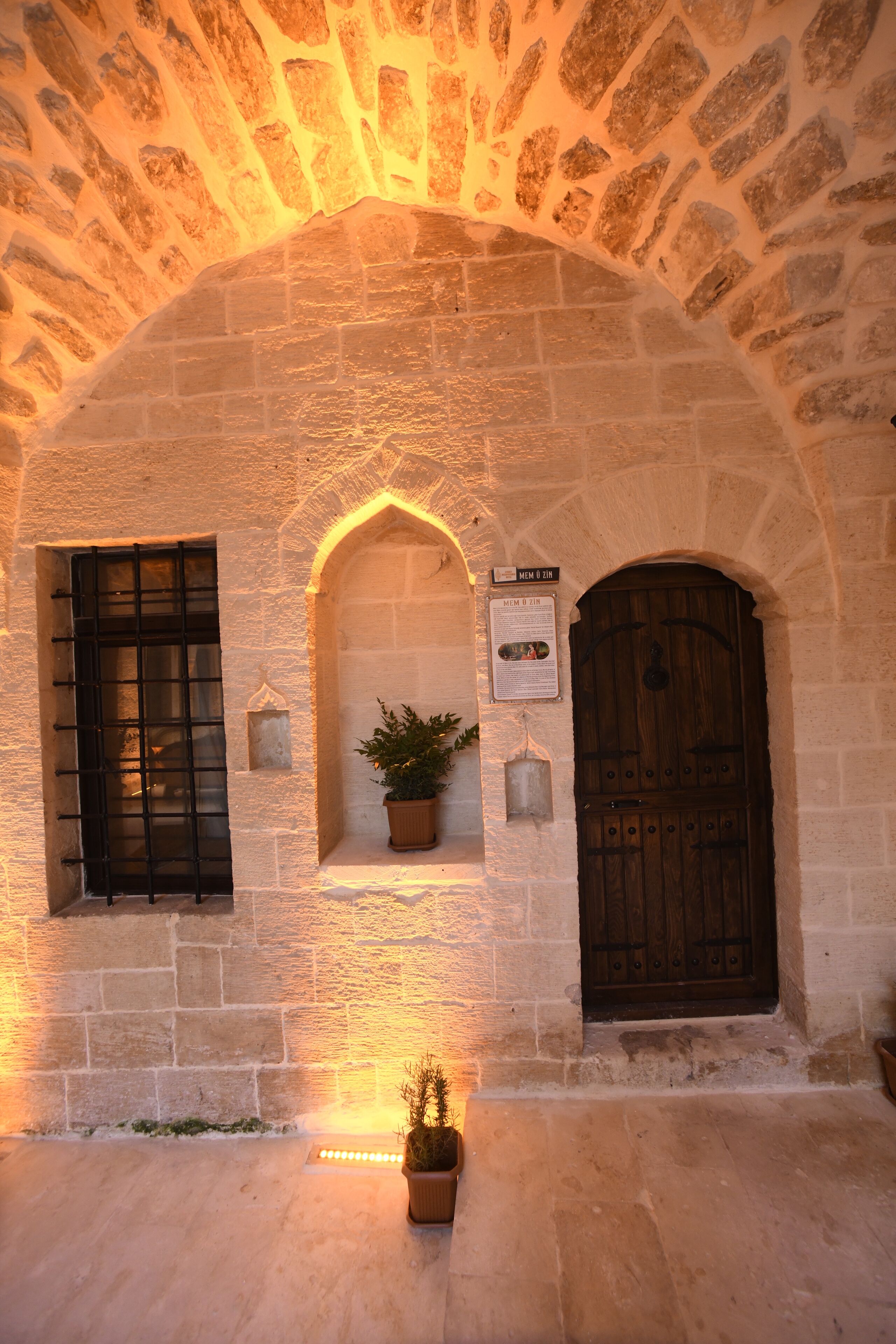 An arched stone doorway with a wooden door and a window with a metal grille.
