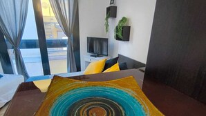 Une chambre d’hôtel moderne dotée d’une grande fenêtre, d ’un téléviseur à écran plat, d’un canapé et d’une œuvre d’art décorative posée sur la table.