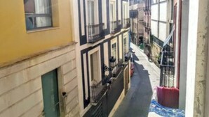 Une rue étroite, bordée de bâtiments des deux côtés, avec des balcons et des fenêtres.