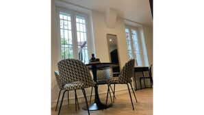 A dining area with a round table and four patterned chairs, large windows, and a view of the outdoors.