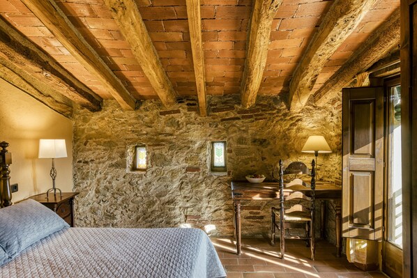 Une pièce rustique en pierre, avec un lit, une table et une chaise.