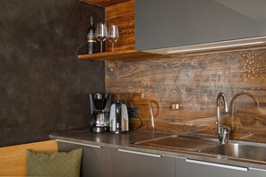 A modern kitchen with a stainless steel sink, wooden backsplash, and a built-in coffee maker.