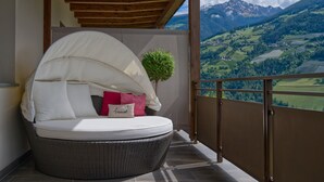 A balcony with a wicker chair, a small potted plant, and a view of a mountainous landscape. - Apartment "Wohnung 2" with Mountain View, Heated Pool & Wi-Fi (Riffiano)