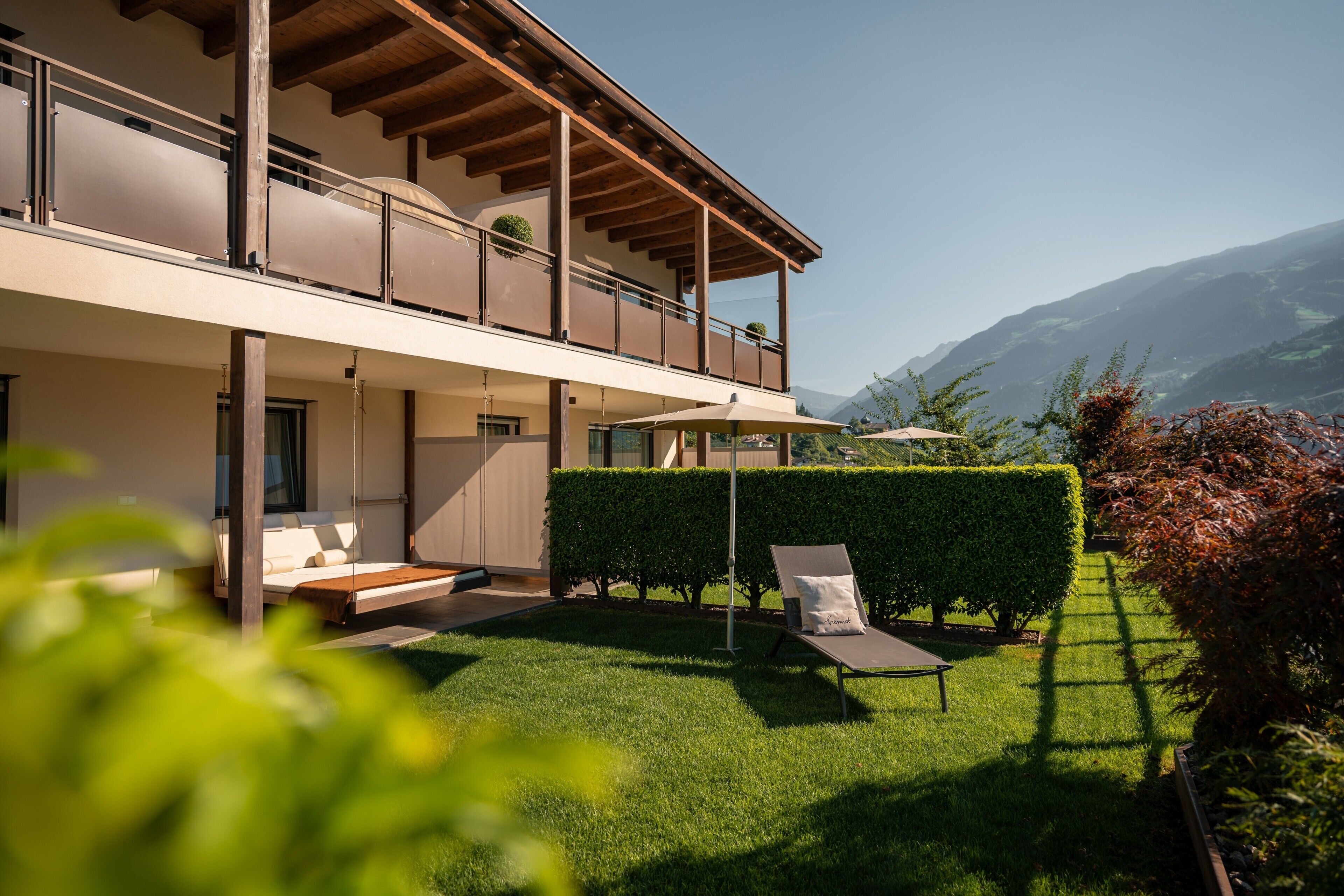 A modern two-story building with a balcony, a well-maintained lawn, and a clear view of the mountains.