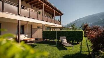 A modern two-story building with a balcony, a well-maintained lawn, and a clear view of the mountains.