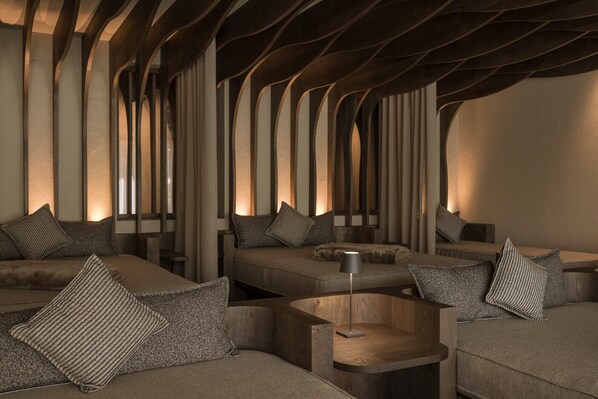 A modern interior with a unique ceiling design, multiple seating areas, and a minimalist aesthetic.