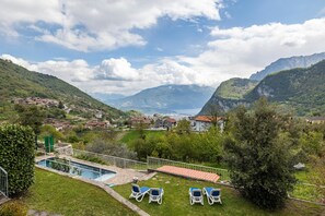 Área da piscina com espreguiçadeiras, uma piscina pequena e vista para uma paisagem montanhosa.