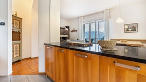 A kitchen with wooden cabinets, a black countertop, and hanging pendant lights.