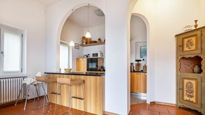 A kitchen with a central island, bar stools, a radiator, and a cabinet with decorative items.