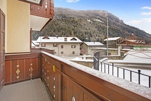 A balcony with a wooden railing, a view of buildings, and a snowy mountain in the background. - Apartment "Monolocale Sole 2" with Mountain View, Balcony & Wi-Fi (Cepina)