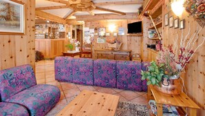Un intérieur chaleureux en bois, avec un canapé, une table en bois et un coin bar.