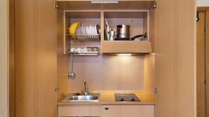 Une petite cuisine équipée d’un évier, d’une cuisinière et d’un égouttoir à vaisselle.