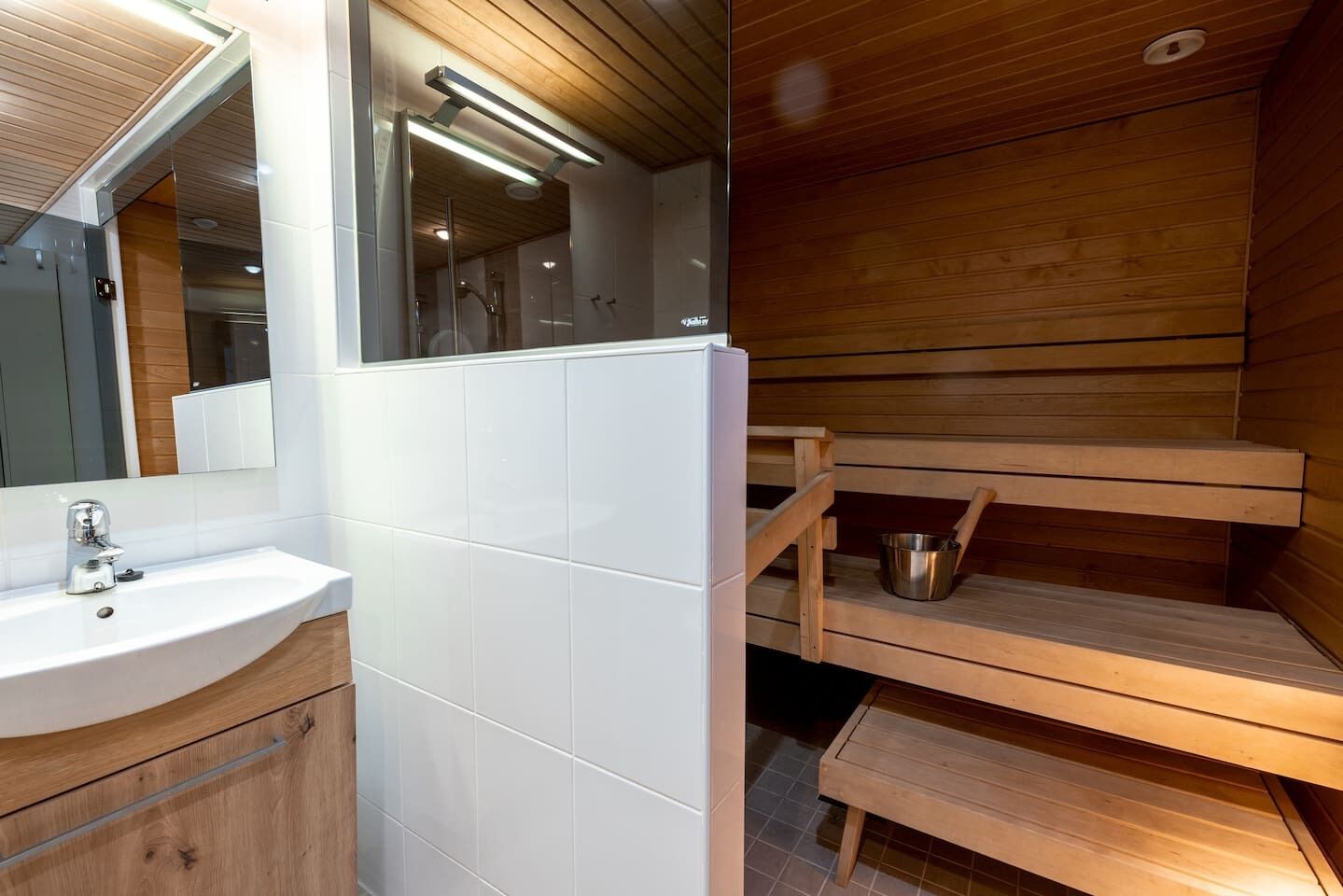 A modern bathroom with a white sink, mirror, and wooden shelves.