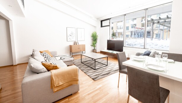 Een moderne woonkamer met een bank, salontafel en een eethoek.