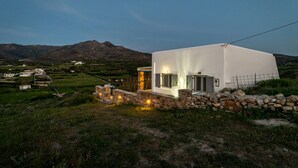 A modern white building with a stone wall entrance, set against a mountainous backdrop. - Kalliston, Romantic Villa with Amazing Sea View (Naxos)