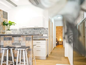 A modern kitchen with a tiled backsplash, white cabinetry, and a central island with bar stools.