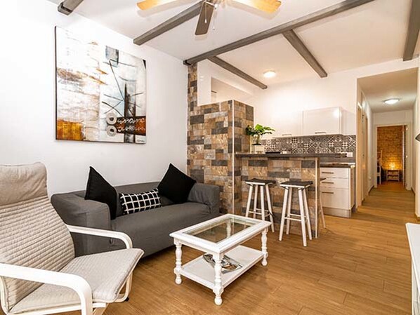 A modern living room with a grey sofa, a white coffee table, and a painting on the wall.
