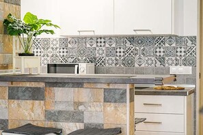 Une cuisine avec un crédence décorée, un four à micro-ondes et une plante.