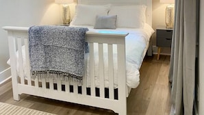 Un dormitorio con cama, mesitas de noche, una ventana con cortinas y vistas al exterior.