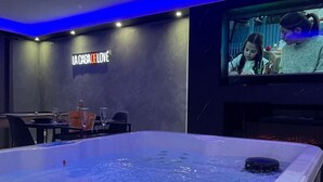 Une chambre dotée d’une grande baignoire, d’un écran de télévision et d’une pancarte sur laquelle on peut lire : « LA CASA DE LOVE ».