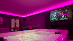 Une pièce dotée d’un grand jacuzzi, d’un écran de télévision diffusant des images du monde sous-marin et d’une affiche sur le mur indiquant : « SOLDES SUR L’AMOUR ».
