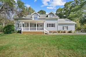 A two-story house with a front porch, a covered entryway, and a small front yard. - Riverwood at Mill Ridge - hot tub, arcades, firepit along Watauga River, walk to pool, tennis (Banner Elk)