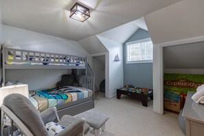 A child's bedroom with bunk beds, a desk, and a bookshelf.