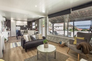 Ein modernes Wohnzimmer mit Küche, Essbereich und einem großen Fenster mit Blick auf das Meer.