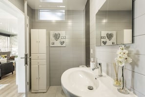 A modern bathroom with a white sink, a mirror, and decorative heart-shaped tiles on the wall.
