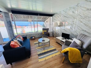 Un salon moderne avec un canapé, un fauteuil, une télévision et une vue sur la ville.