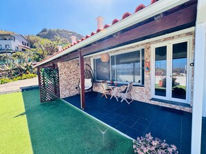 A house with a patio, a hanging chair, a table, and a window. - Studio Matilde and Joaquim, panoramic sea view (Porto da Cruz)