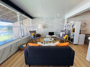A modern living room with a sofa, armchairs, a coffee table, and a bookshelf. - Studio Matilde and Joaquim, panoramic sea view (Porto da Cruz)