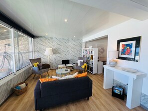 A modern living room with a sofa, armchairs, a coffee table, a TV, a bookshelf, and a fireplace.