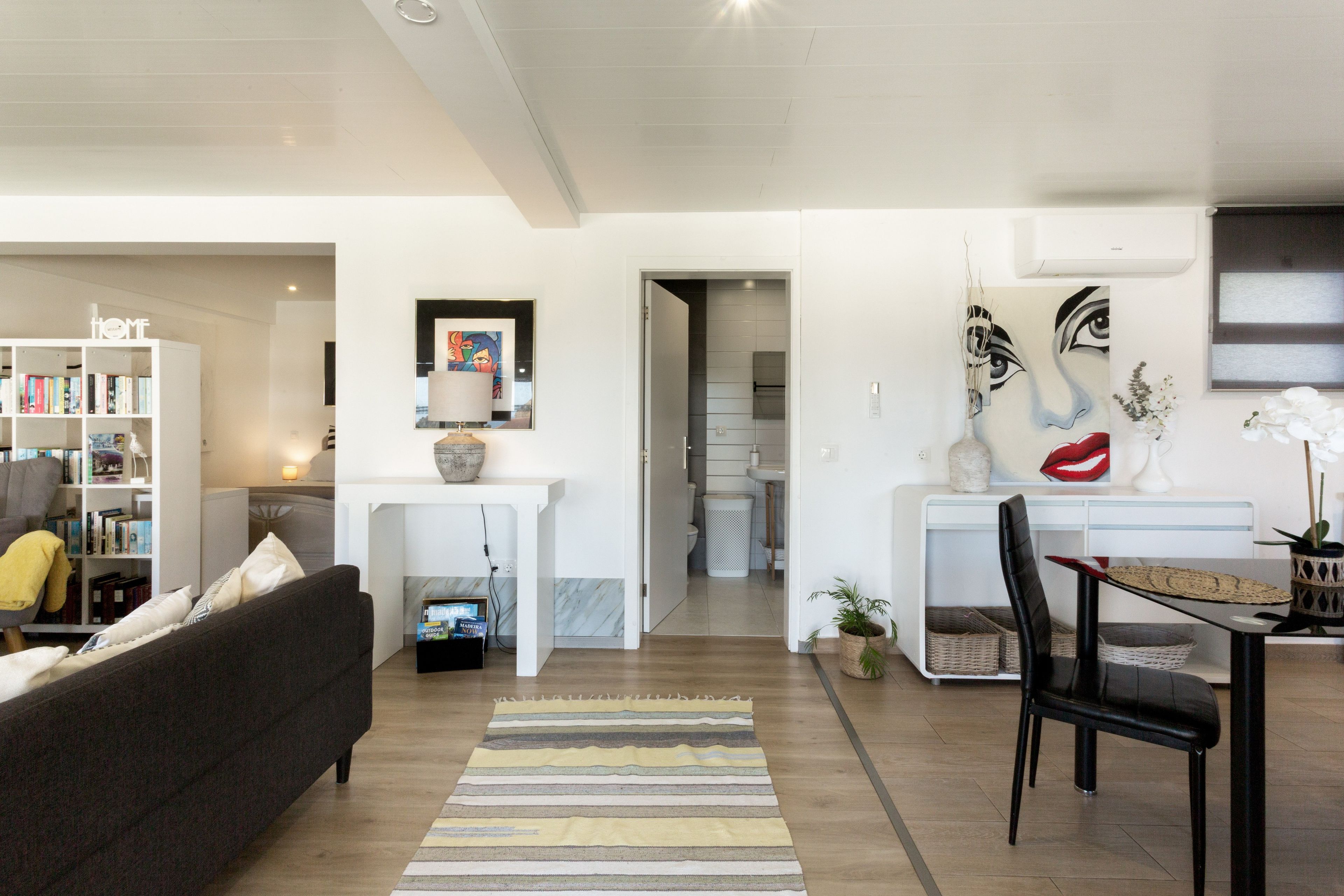 A modern living room with a sofa, a coffee table, and a dining area with a chair and table.
