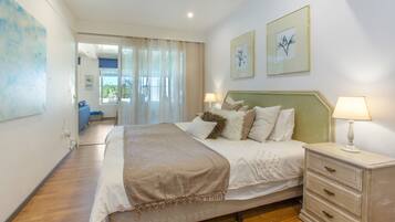 A bedroom with a bed, bedside tables, a dresser, and artwork on the walls.