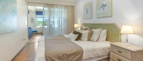 A bedroom with a bed, bedside tables, a dresser, and artwork on the walls.